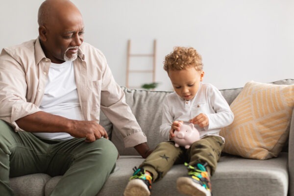 Grandfather and grandson placing coins into a piggy bank