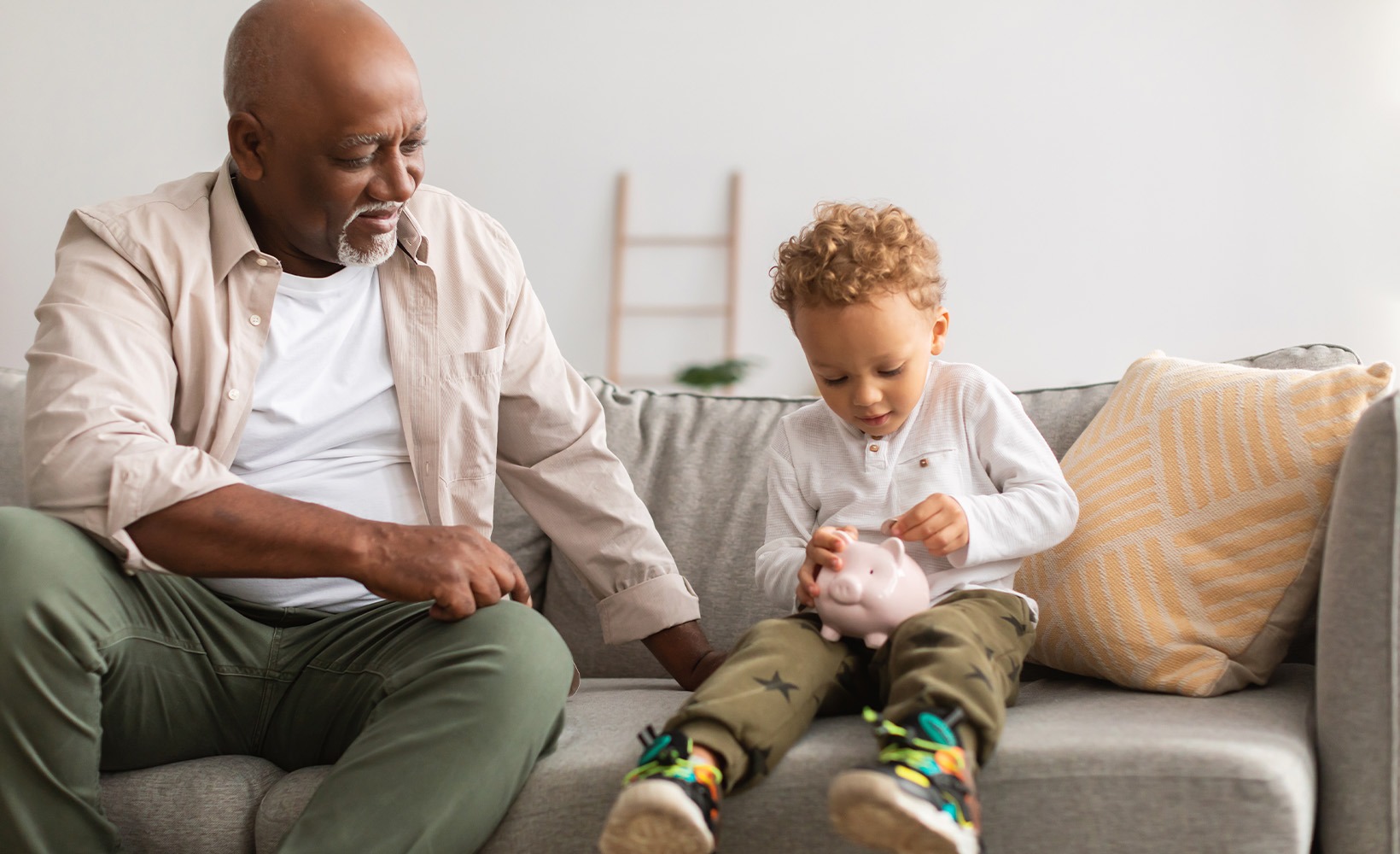 Grandfather and grandson placing coins into a piggy bank