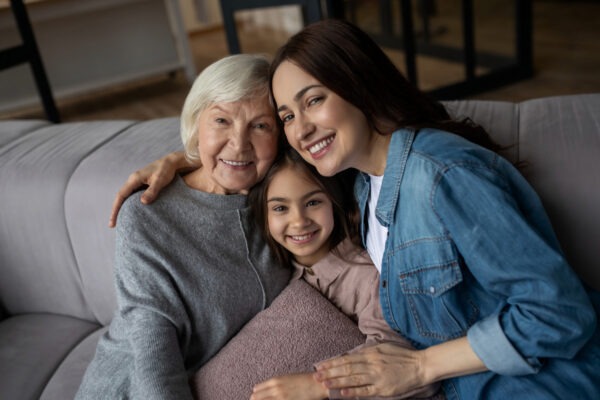 Grandmother, mother and granddaughter posing for picture on couch.