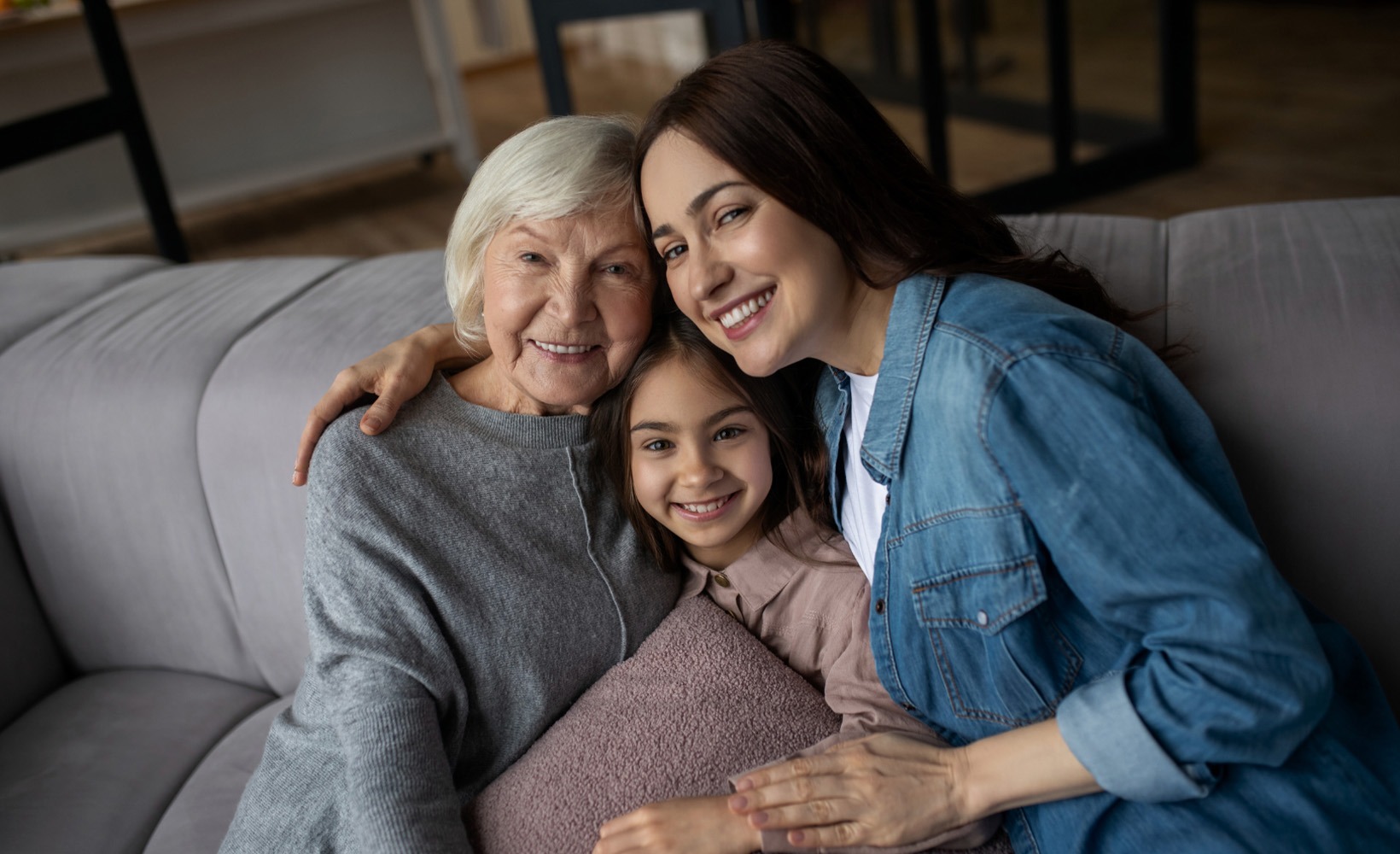 Grandmother, mother and granddaughter posing for picture on couch.